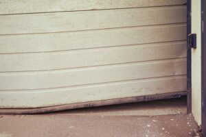 can a bent garage door be repaired? A bent garage door at the weatherproofed base.