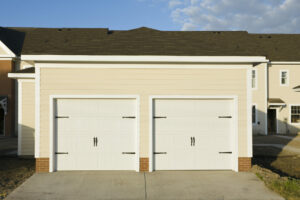 Two, white carriage style garage doors on a townhouse.