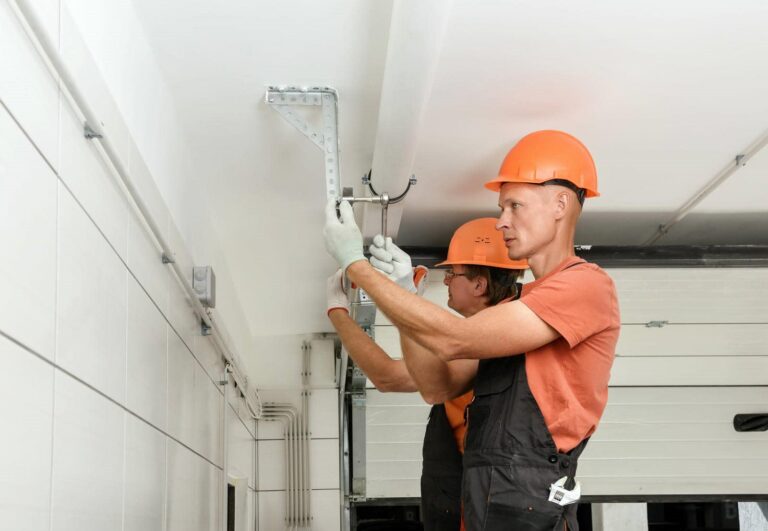 Two workers installing garage door components.