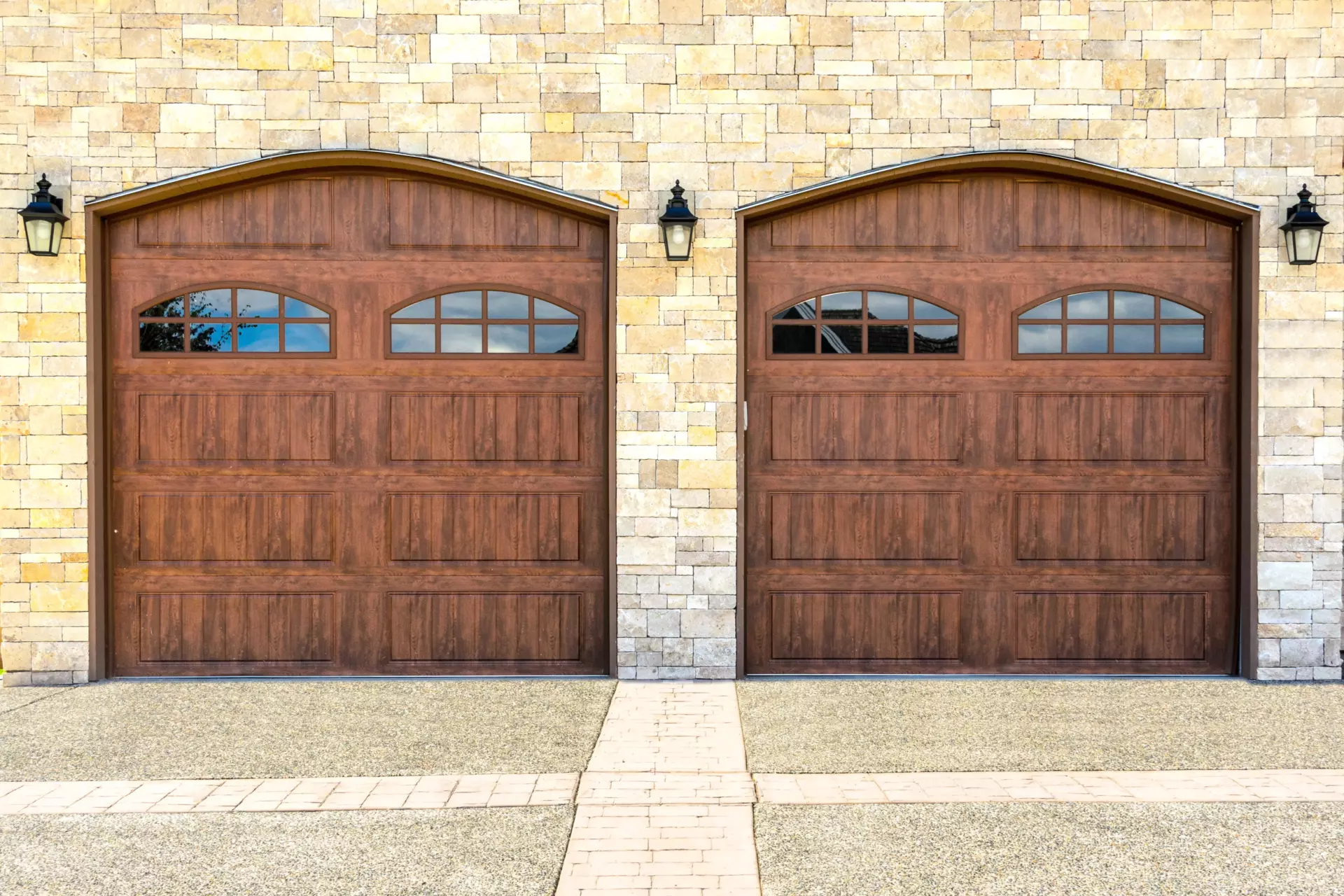 Two wood paneled luxury modern garage doors in a brick house.