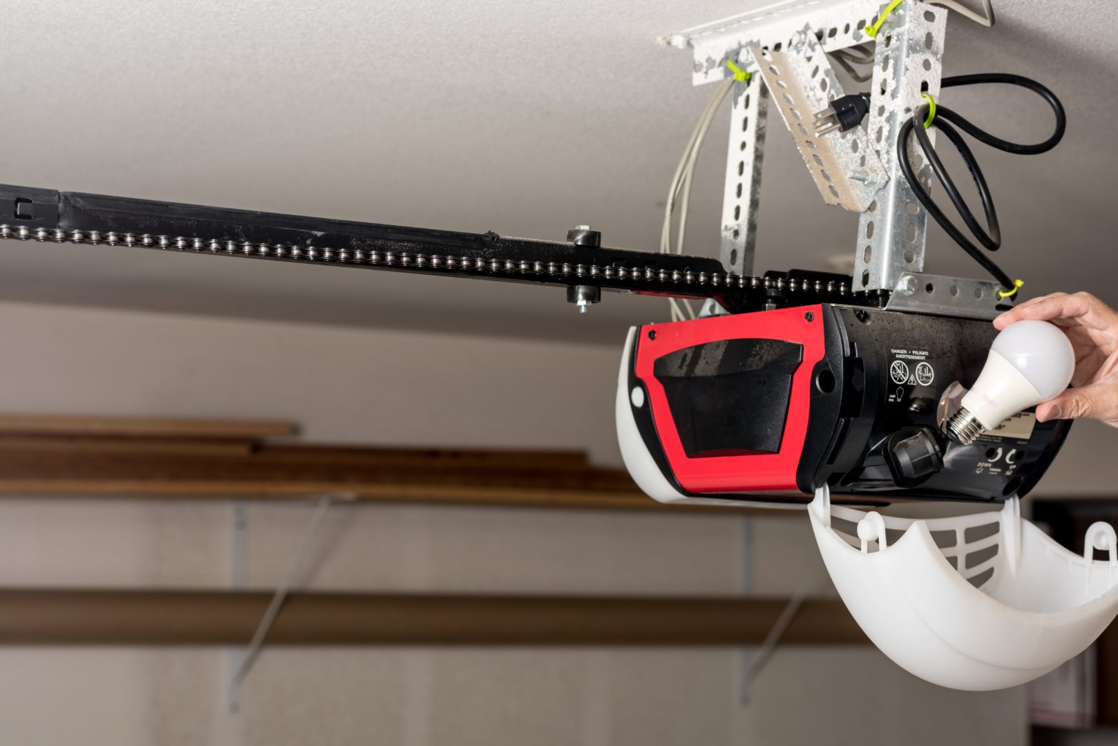 A garage door opener owner changing its LED lightbulb. Similar in style to the Liftmaster WLED, a battery backup garage door opener.