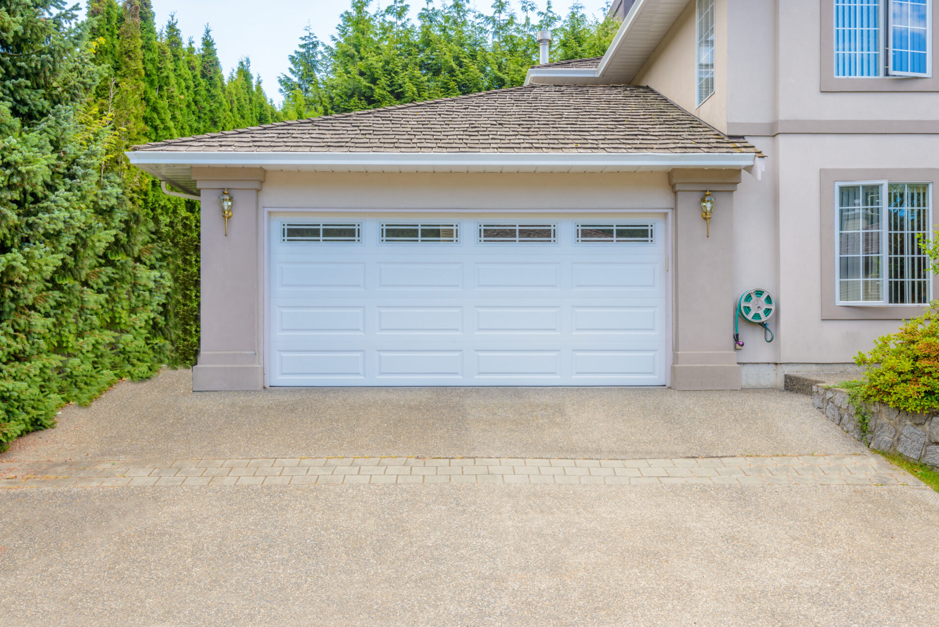 Door Maintenance and Repair. A modern brown faux wooden exterior garage door with four small horizontal glass windows