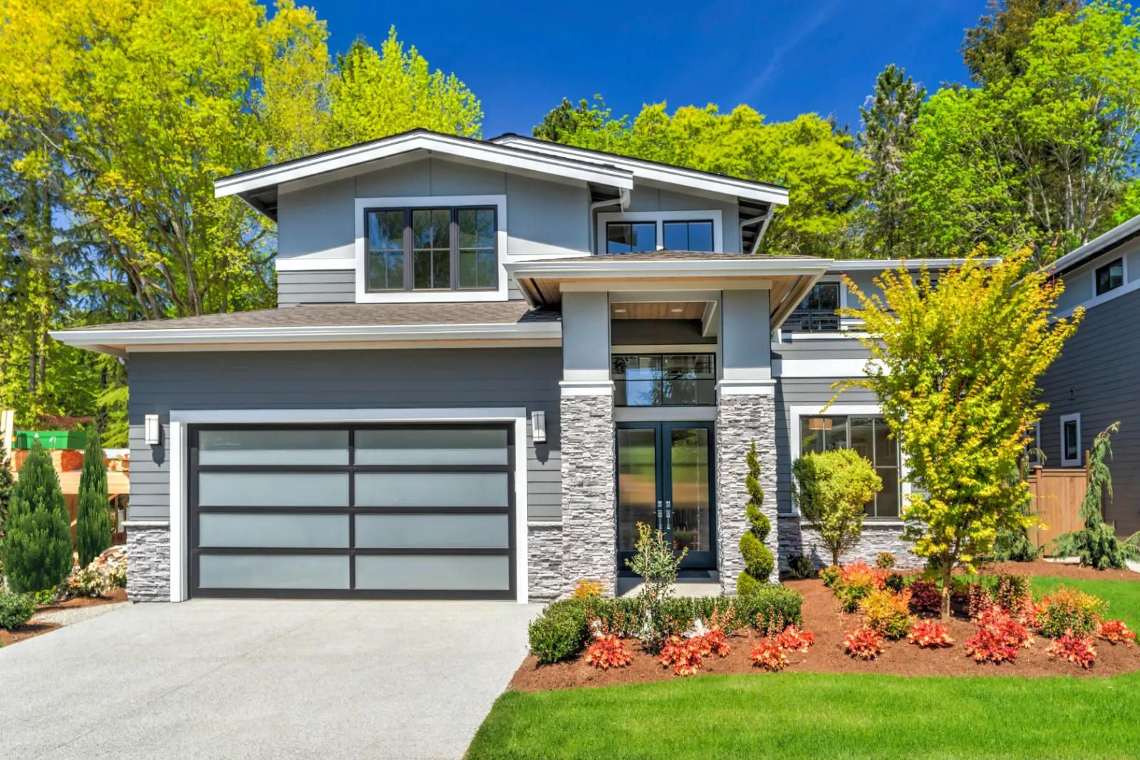 Local Garage Door Installers installed a Modern contemporary house exterior with luxury details landscaping stone wood glass lots of large windows