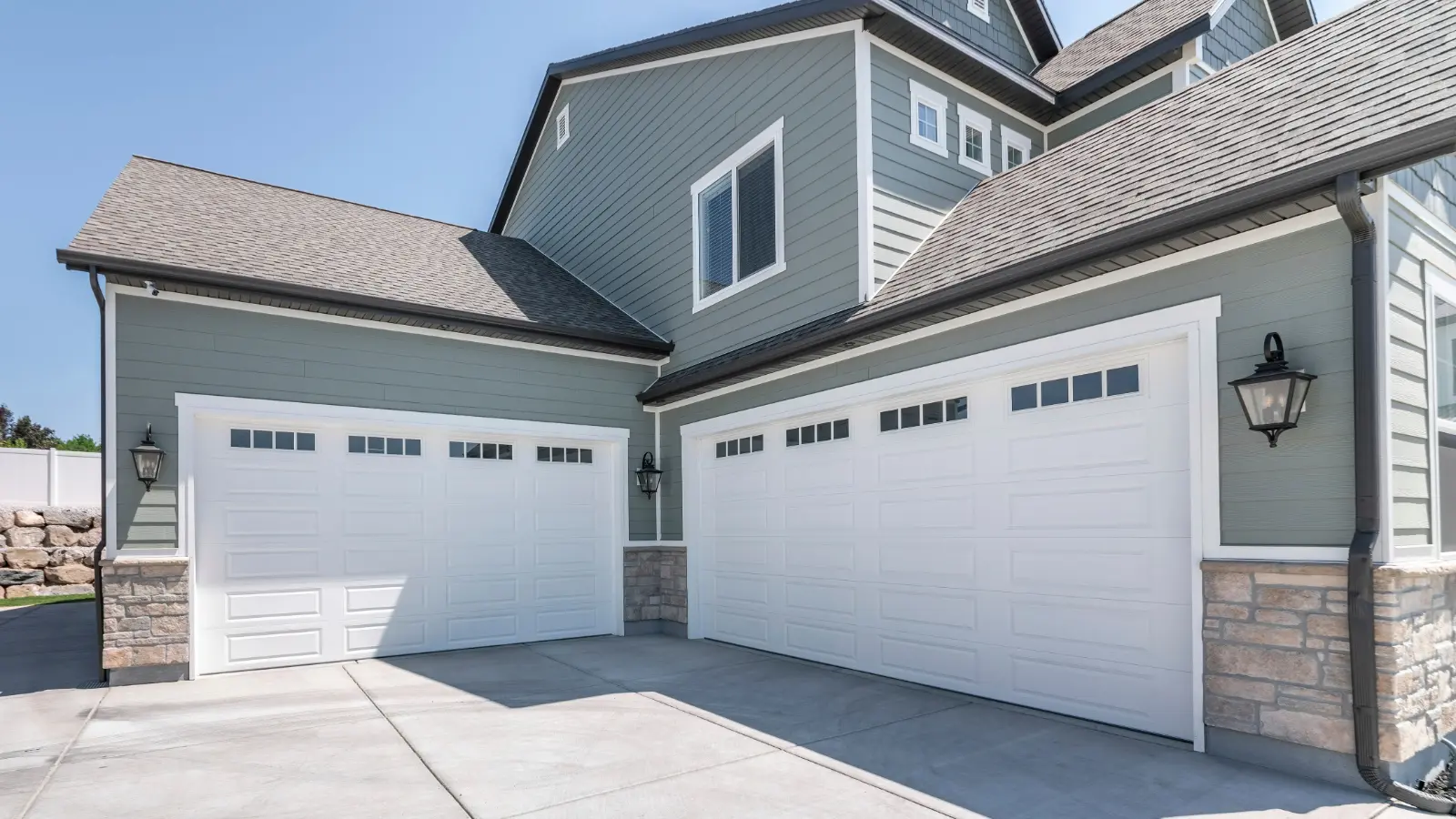 Professional Garage Door Installation Pano-Exterior-of-a-house-with-concrete-driveway-and-two-closed-white-garage-doors-with-windows