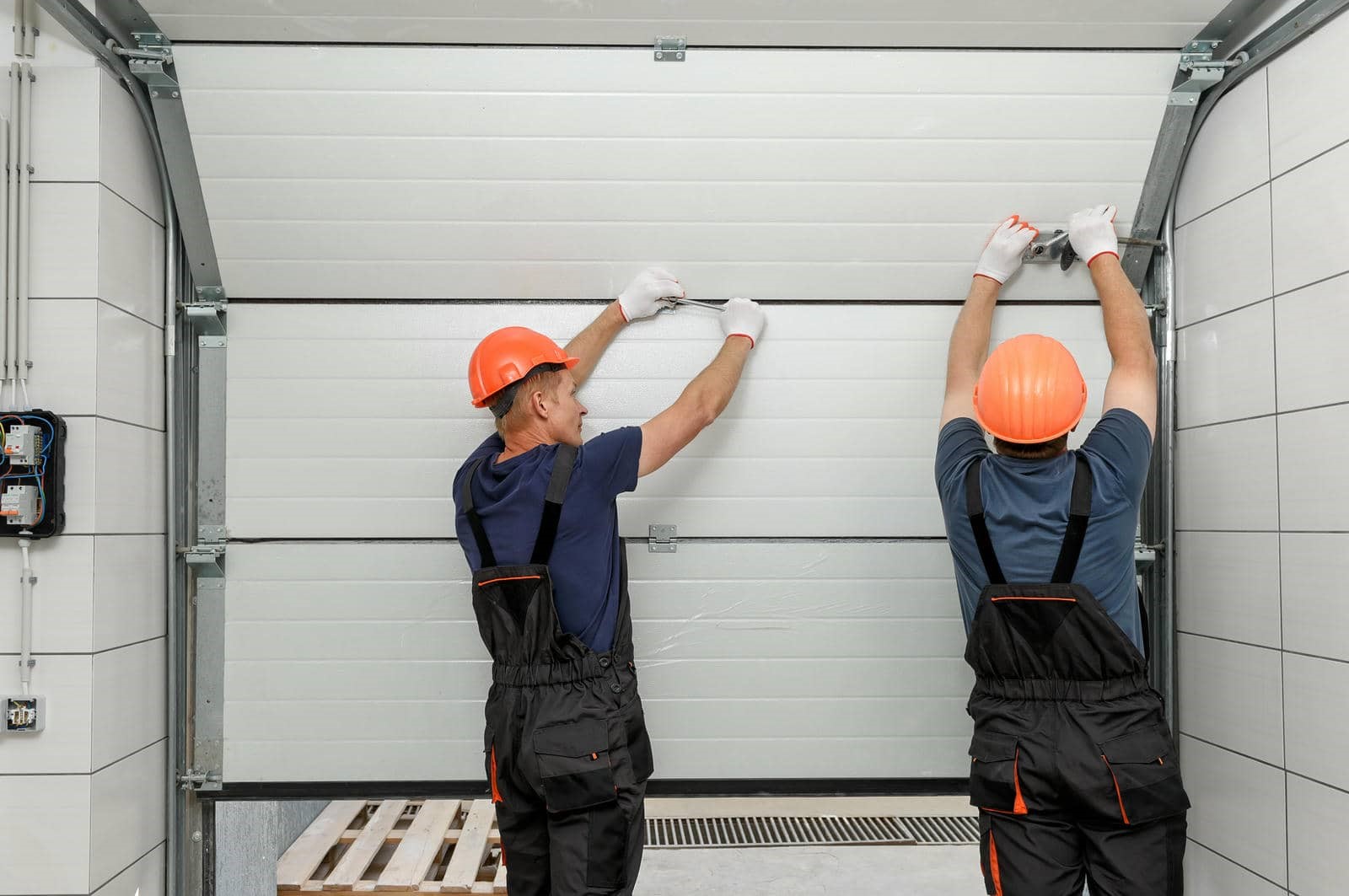 Two workers installing a garage door.