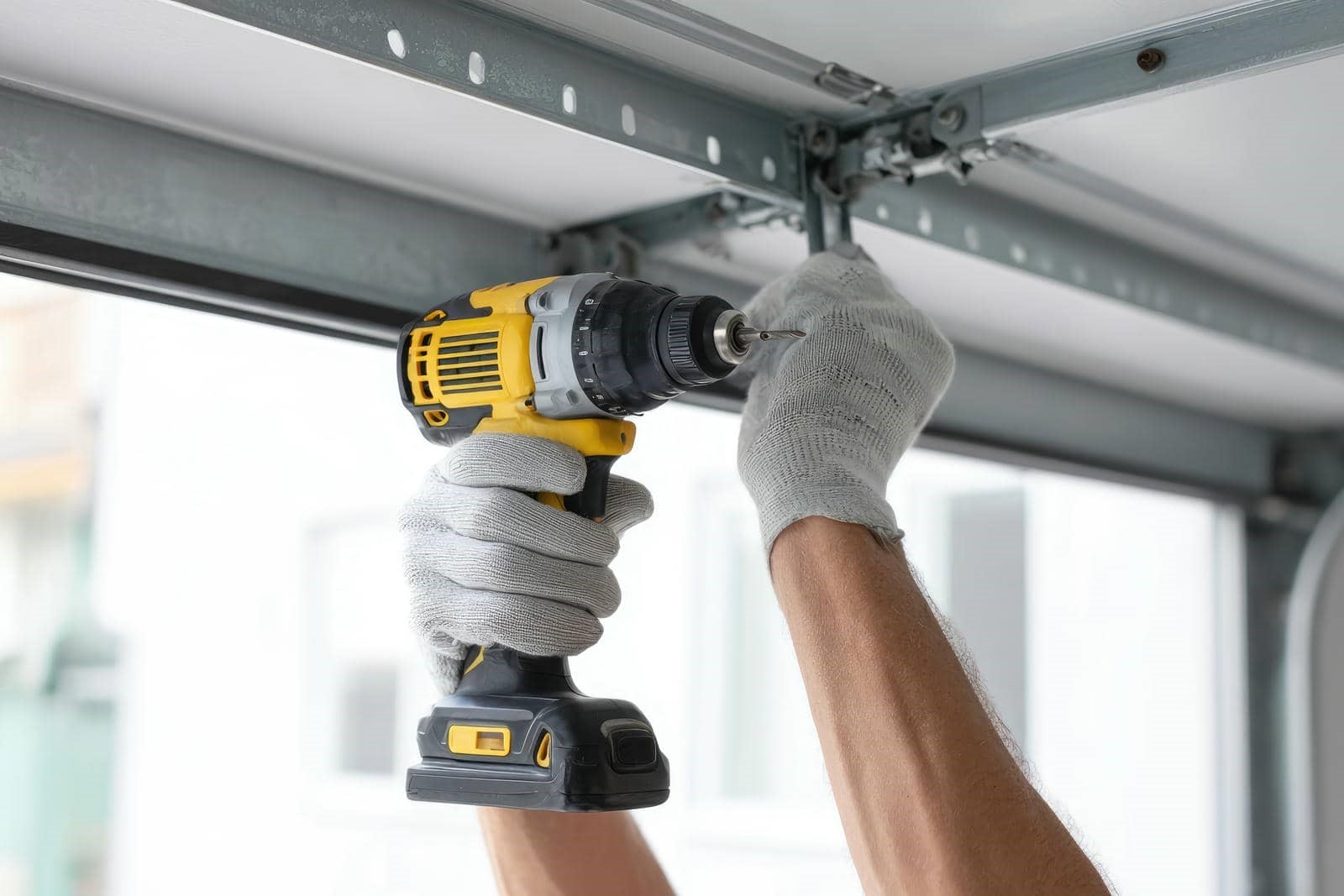 Person using a power drill on garage door