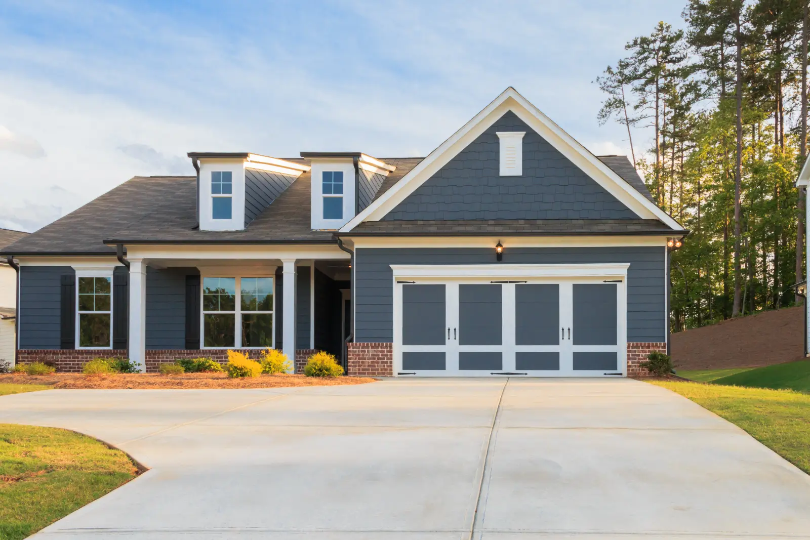 Blue house with large driveway showcasing the best garage door models for enhanced security and curb appeal.