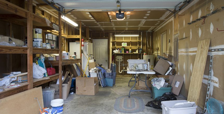 A messy garage with an open garage door. Cleaning out the garage is the perfect Spring activity.