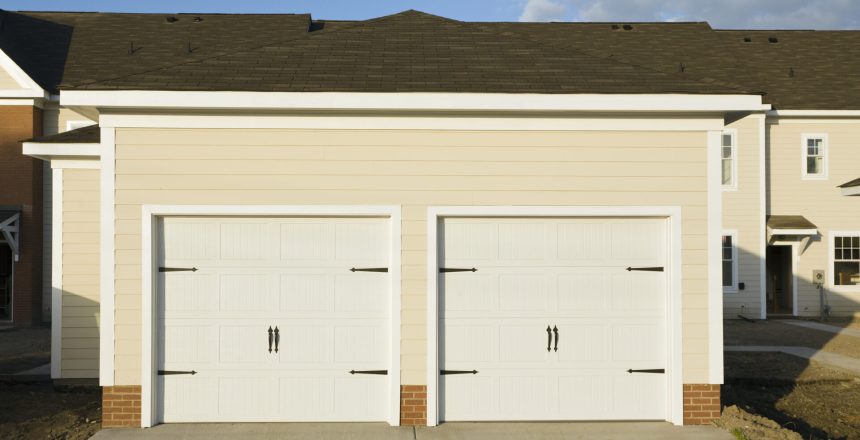 Two, white carriage style garage doors on a townhouse.