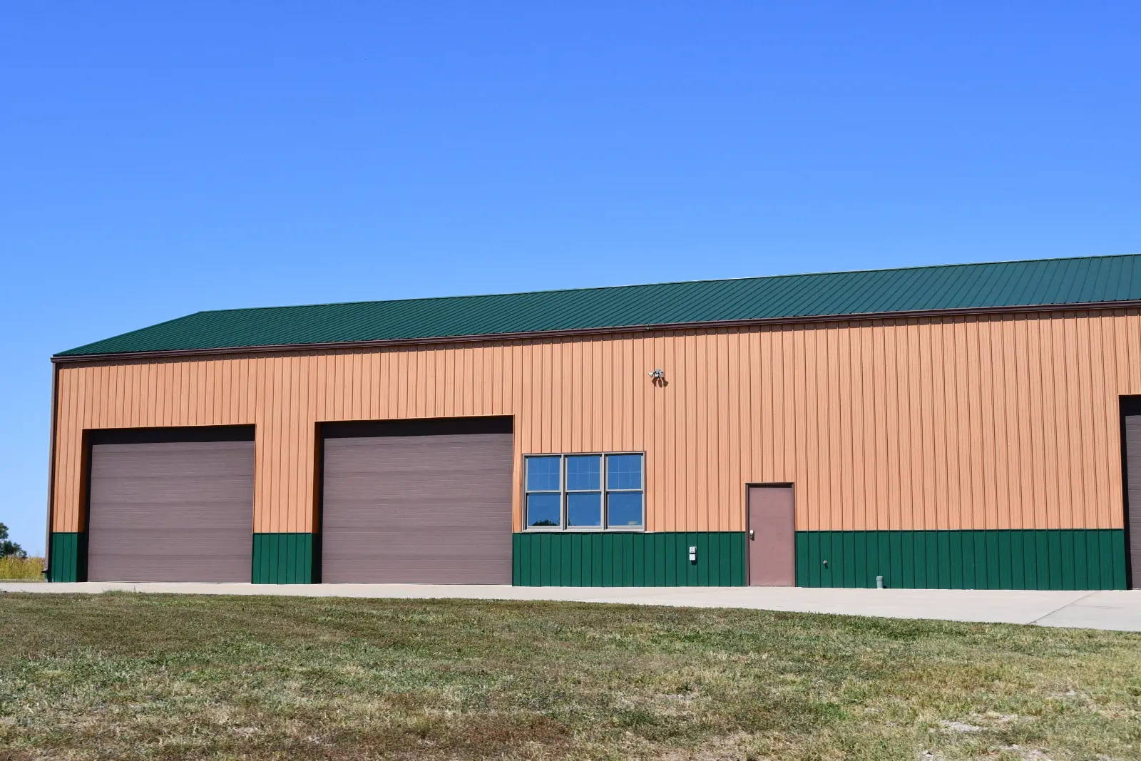 new peach and green metal building with Green Garage Door for a stylish and sustainable touch to your property.