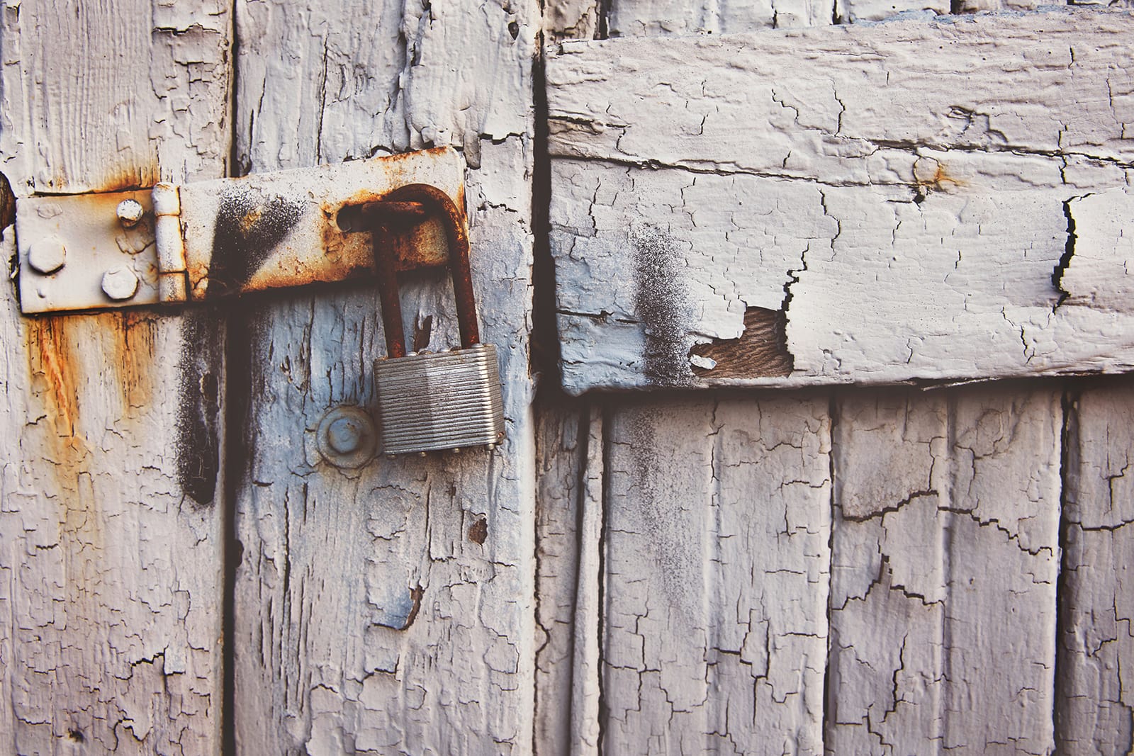 Proper garage door security means more than a lock. A rusted lock on a dilapidated garage door.