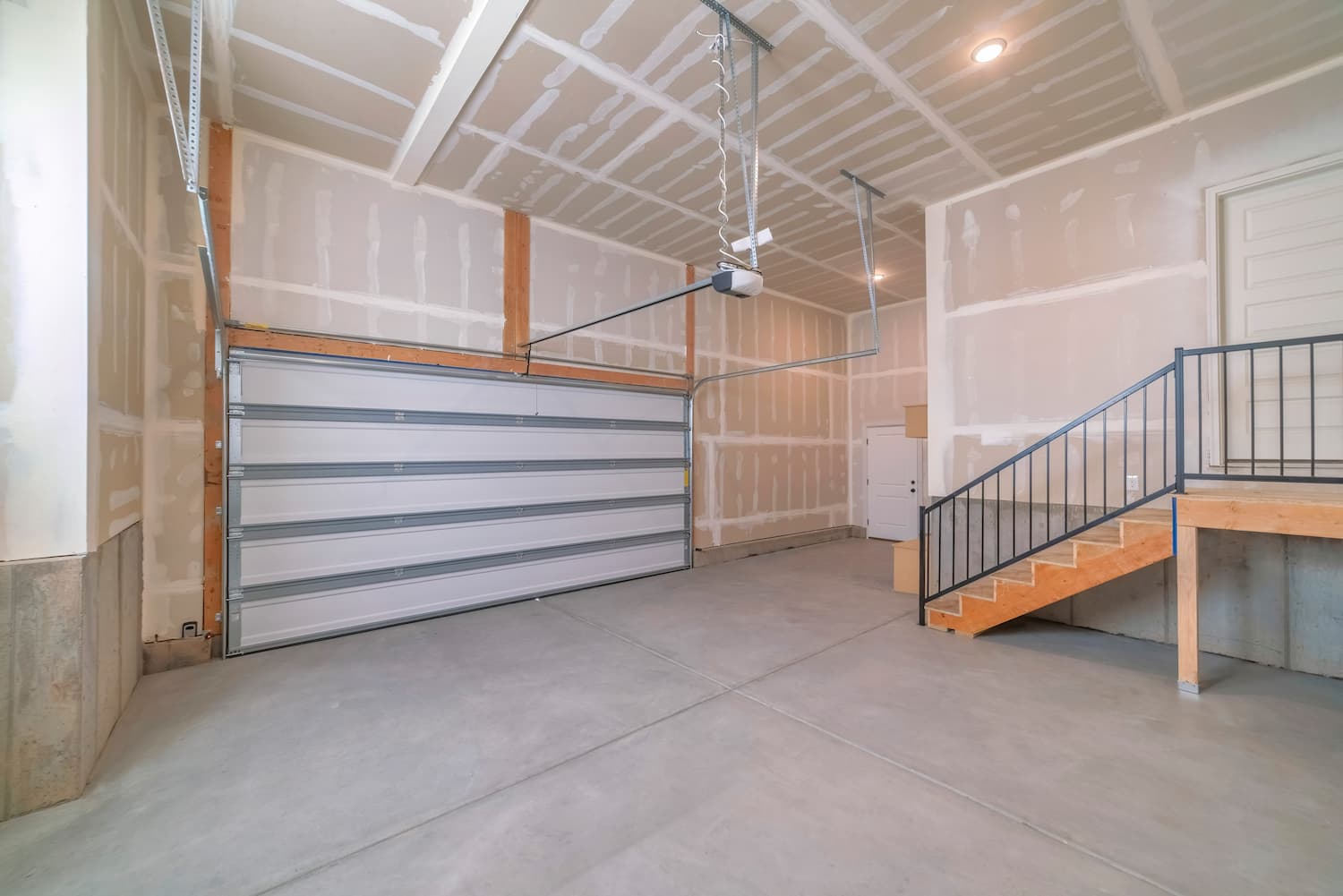 Sectional garage doors have many horizontal panels that take up less space when moving up or into place. A view of a sectional garage door from inside a newly built garage.